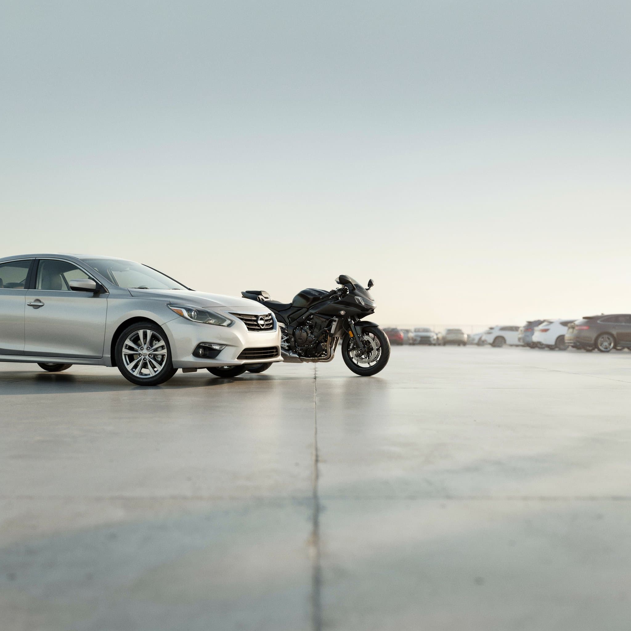 A used car and motorcycle parked in a dealership lot